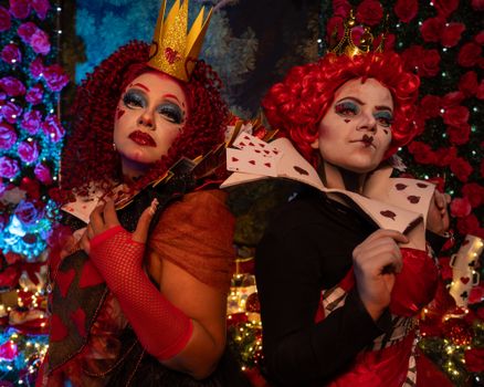 Vibrant depiction of two cosplay queens inspired by Alice in Wonderland with intricate art makeup.