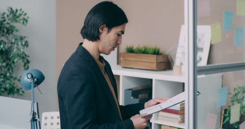 Free Young man analyzing paperwork in modern office setting. Stock Photo