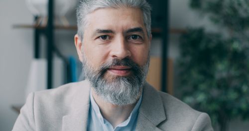 Free Close-up portrait of a mature man with a grey beard indoors. Stock Photo