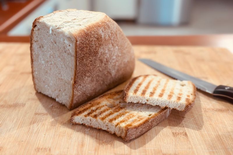 Rustic loaf of bread with sliced pieces on a wooden cutting board, ready to serve.