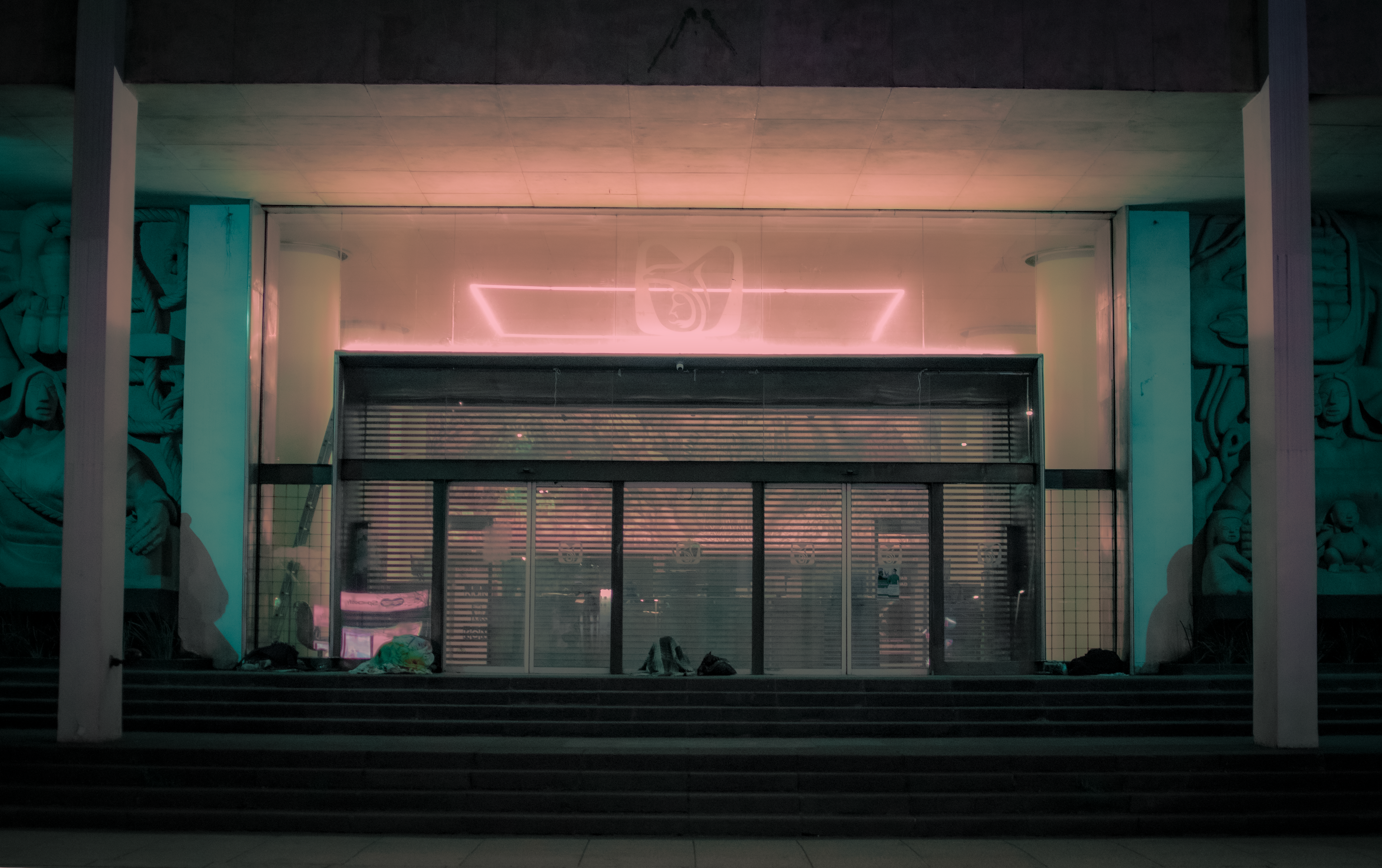 Urban facade with neon lights and closed shutters during night, creating a moody atmosphere.