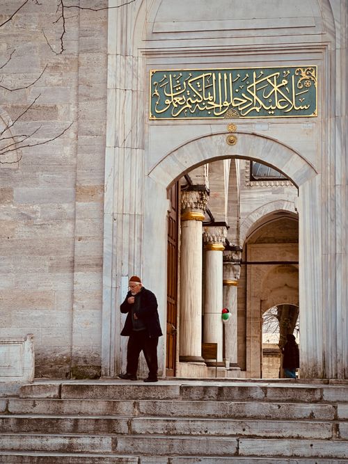 Free A man walks past a grand entrance of a historic mosque in Istanbul, Türkiye, showcasing intricate architecture. Stock Photo