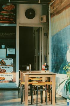 Charming outdoor cafe with wooden tables, stools, and enticing menu displays.