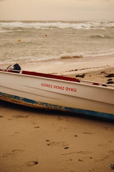 Boat named 'Güneş Deniz Öykü' on a sandy beach during winter at sunset.