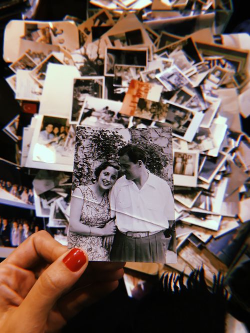 Free Hand holding a vintage couple photo over a pile of nostalgic photographs. Stock Photo
