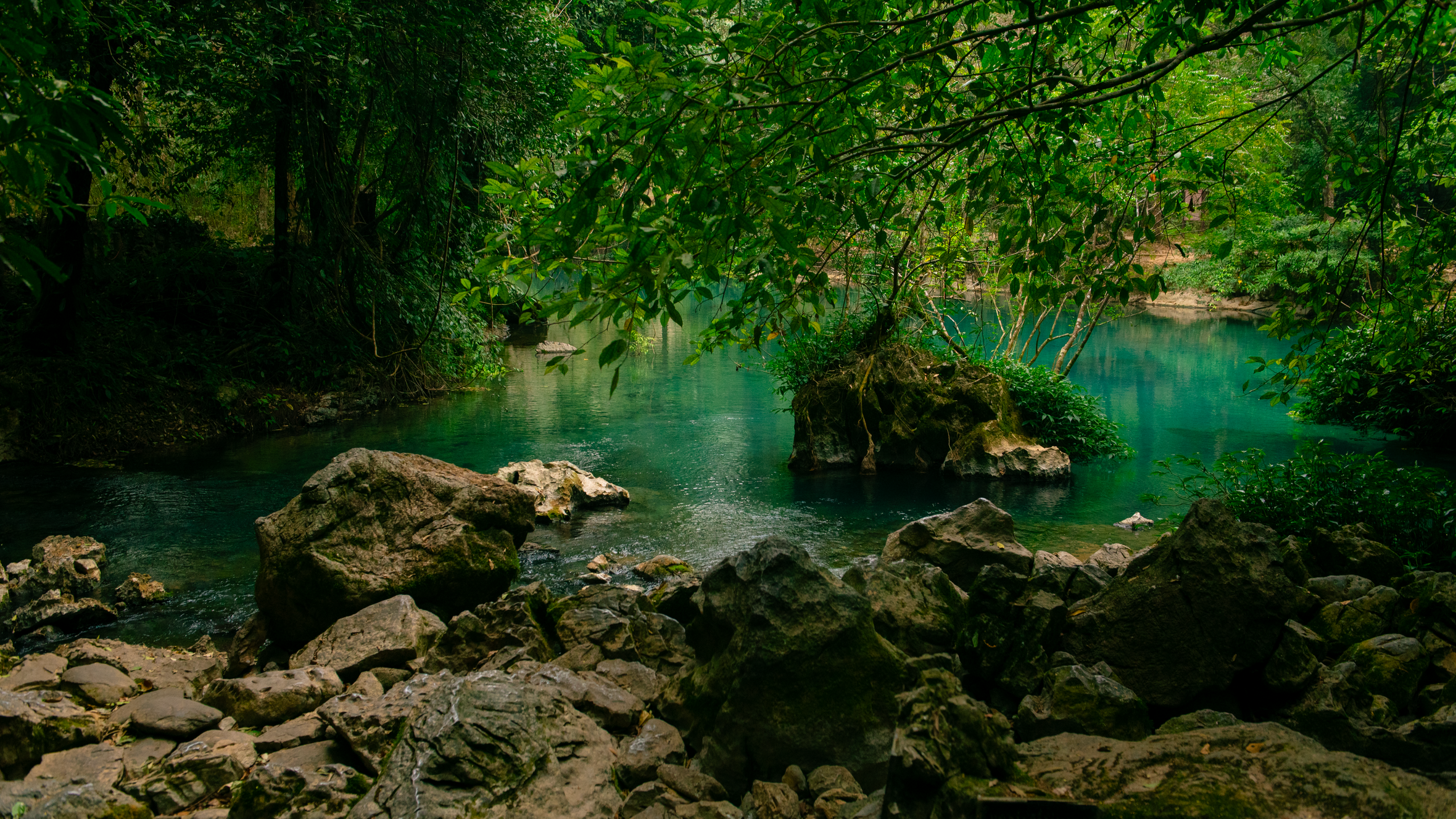 A tranquil river scene surrounded by lush greenery and rocks in Cao Bằng, Vietnam.