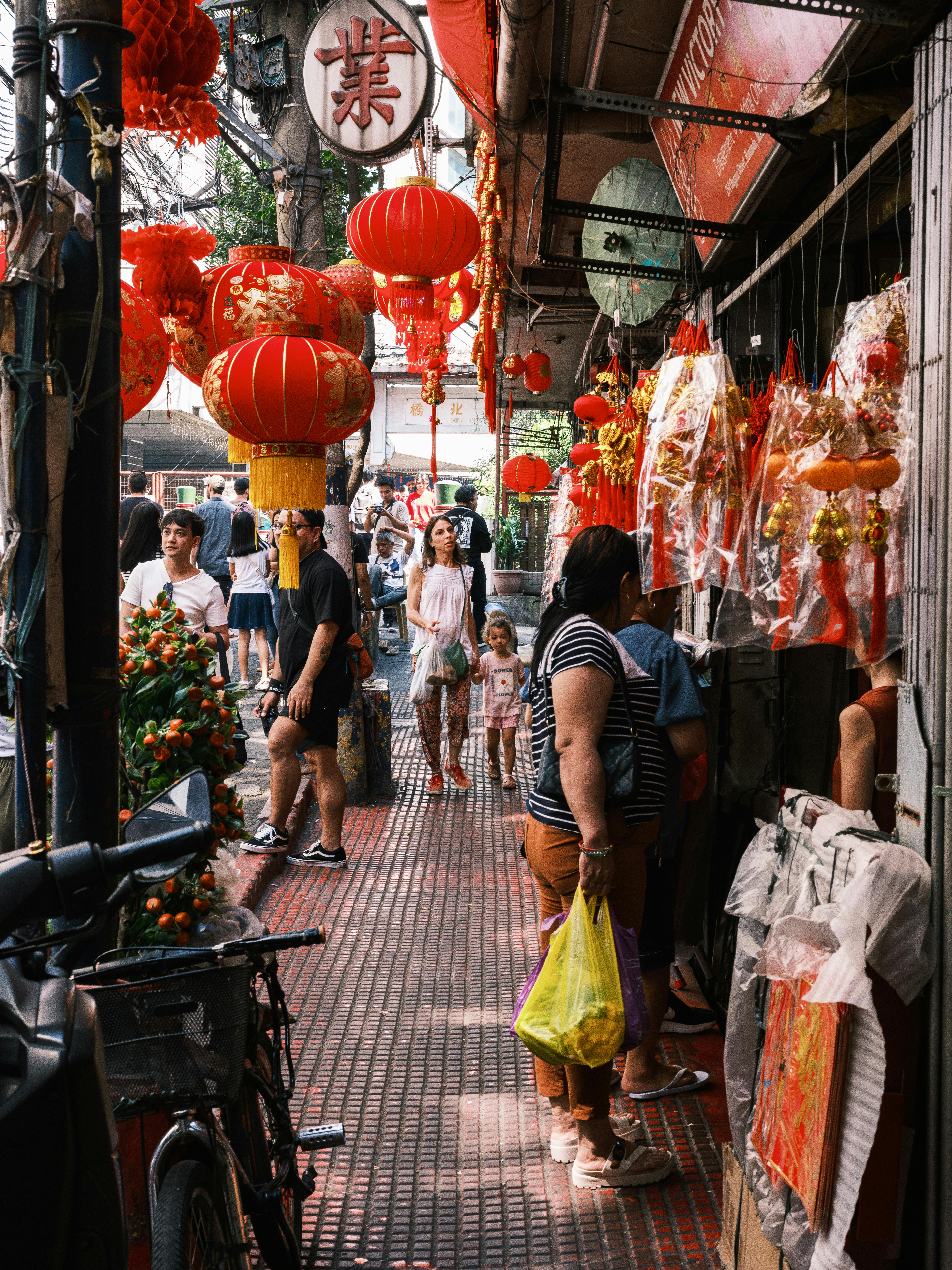A lively street market with red Chinese lanterns and diverse shoppers, capturing cultural richness.