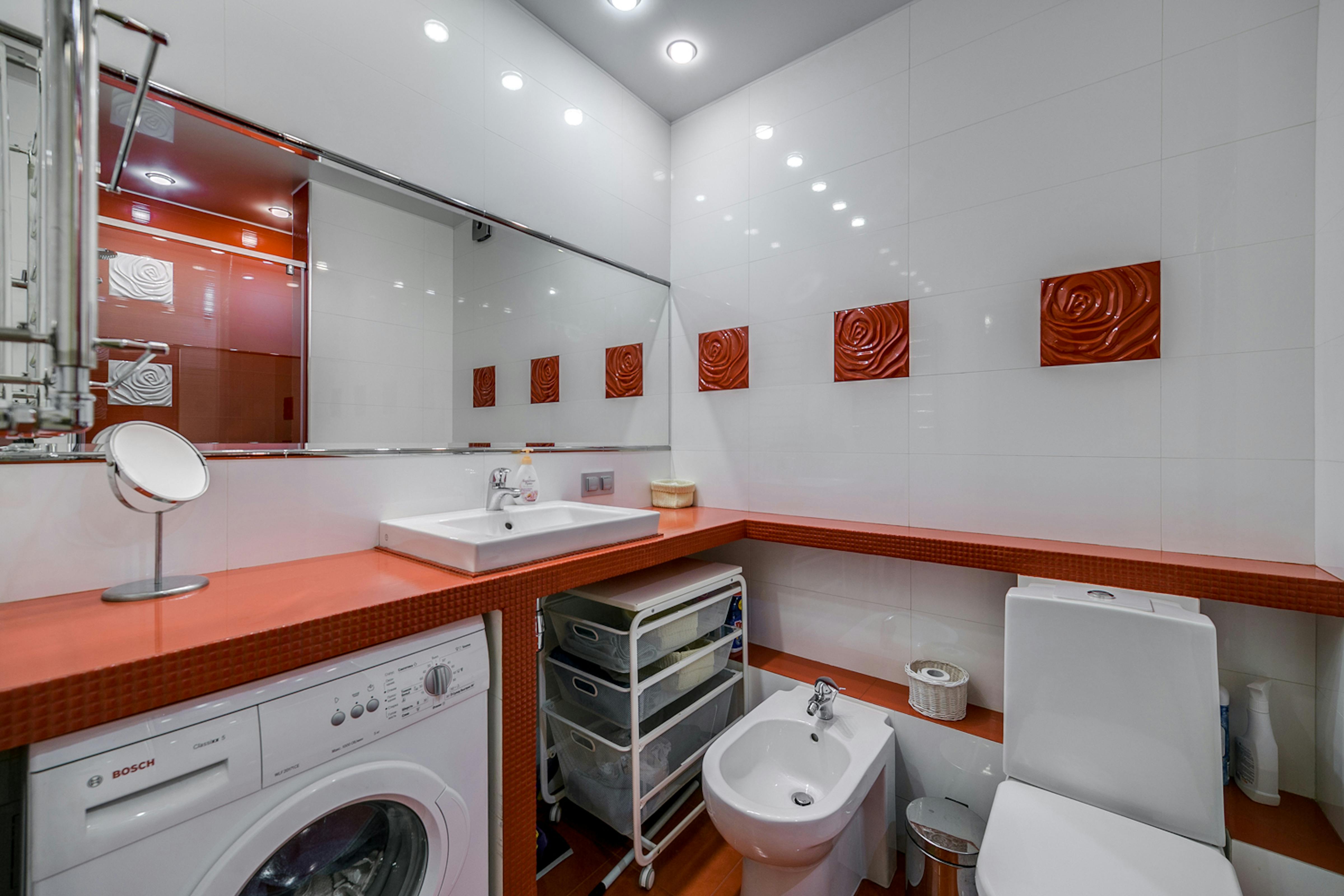 Kompakte Wäschezone im modernen Badezimmer mit Arbeitsplatte über der Waschmaschine in Weiß und Hellgrau