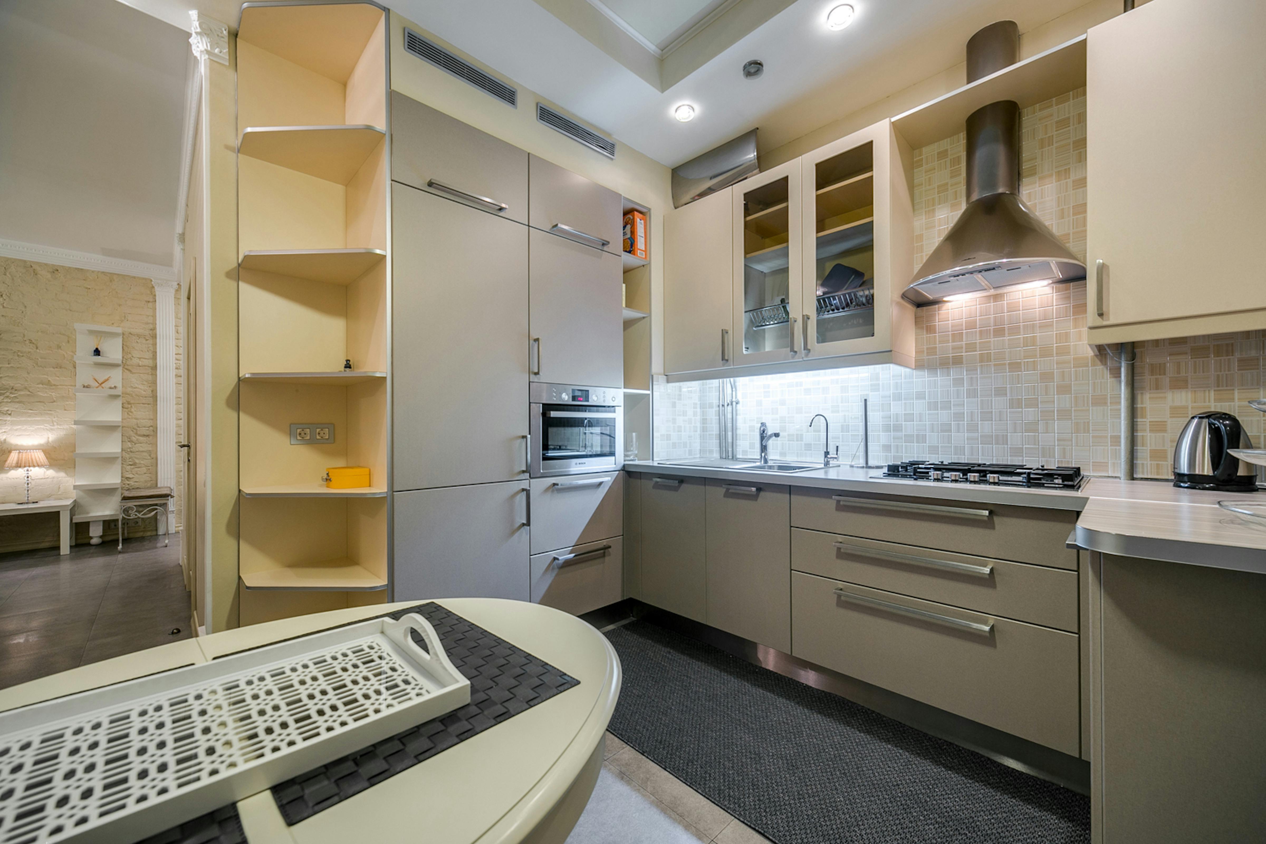 Kleine moderne Küche mit hellen Fronten, kompaktem Layout und klarer Arbeitsfläche in Beige und Weiß