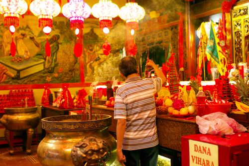 Free A person performs a ceremonial ritual in a Chinese temple adorned with vibrant decorations in Jakarta, Indonesia. Stock Photo