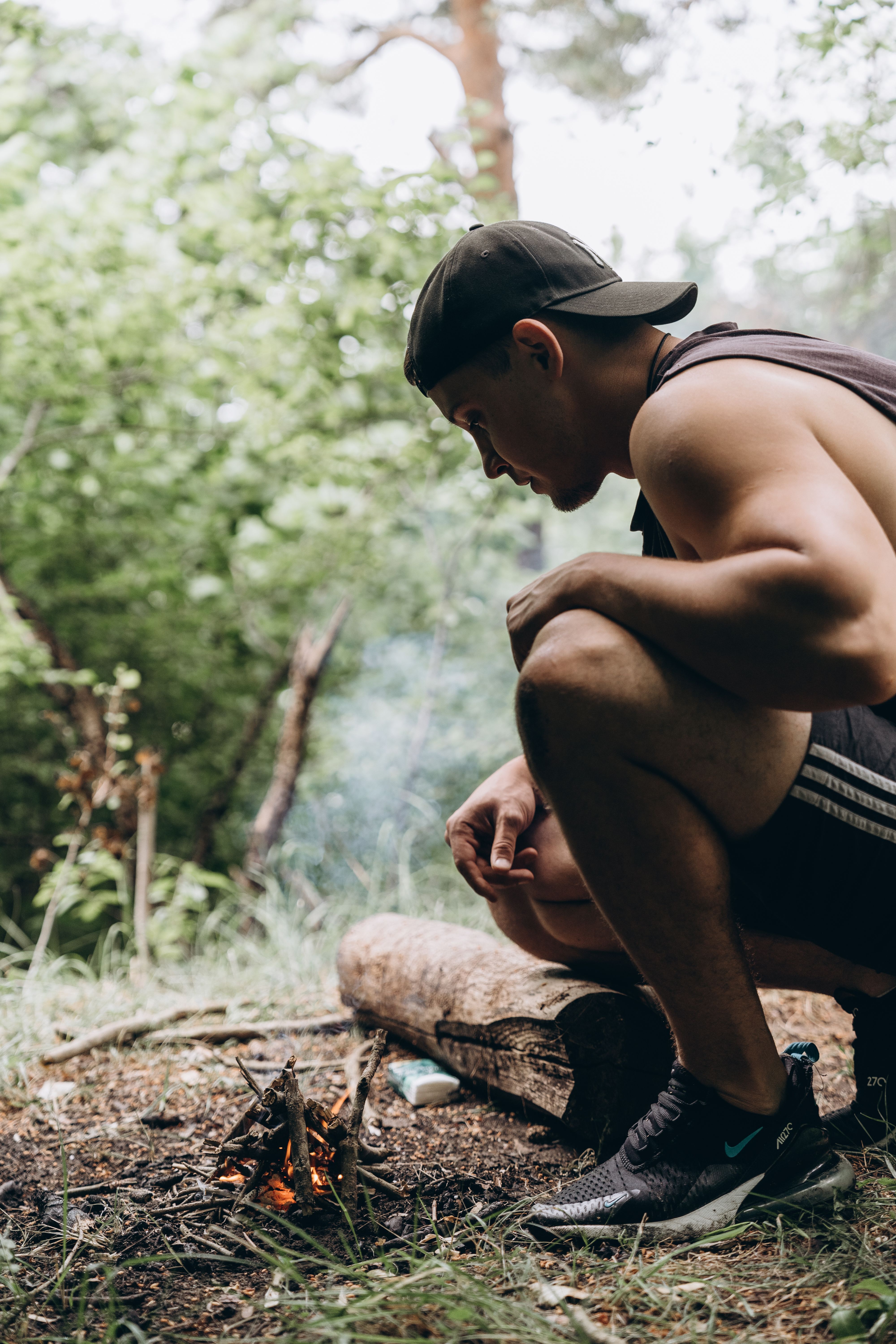 Young Man Starting a Campfire in Forest Setting · Free Stock Photo