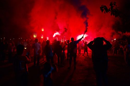 Free Silhouettes celebrate with red lanterns and smoke in a vibrant night festival in Jakarta. Stock Photo