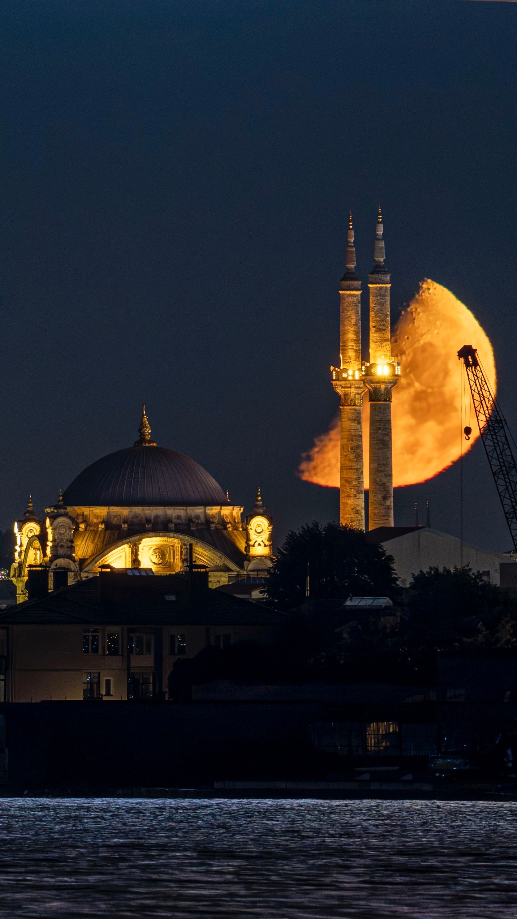 Stunning night view of an Istanbul mosque with a bright moon behind.
