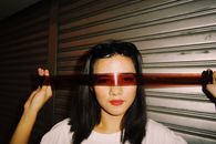 一位女性在城市环境中用胶片当作太阳镜的创意肖像