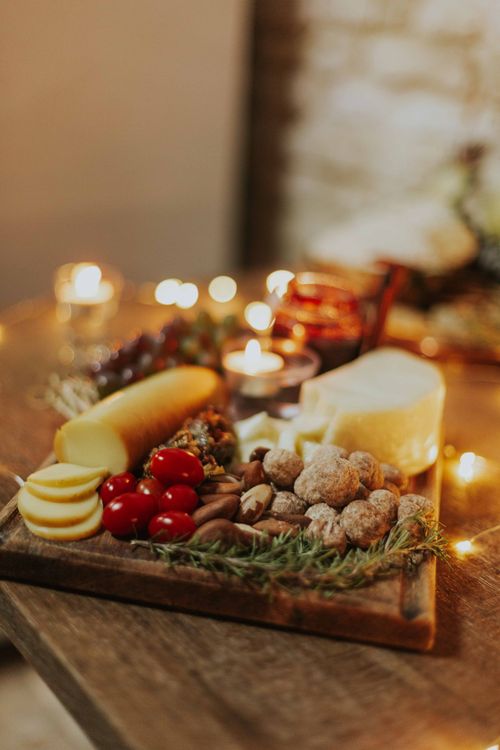 Free A cozy cheese and charcuterie board with candles, featuring fresh cheeses, nuts, and tomatoes for a festive gathering. Stock Photo