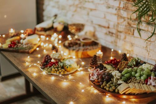 Free Cozy indoor scene of a beautifully arranged cheese and fruit platter with festive candles and lights. Stock Photo