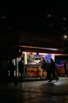 A lively street food stall in Istanbul offers doner kebabs and drinks, captured at night.
