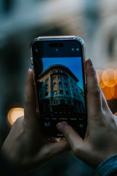 Hands holding a smartphone capturing a historic building in İstanbul, Türkiye.