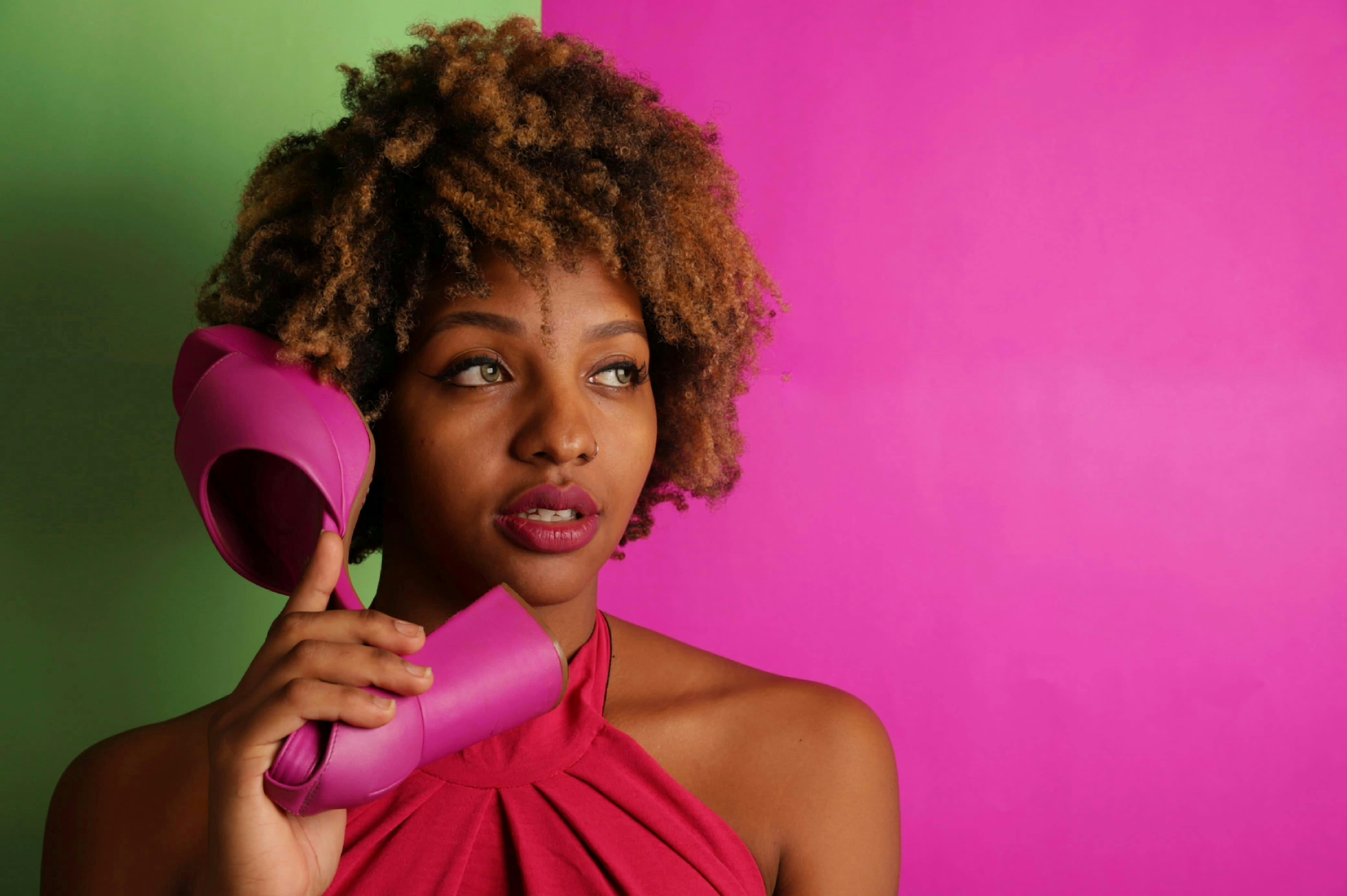 bezplatná Módní žena používající růžovou botu jako telefon na živém pozadí. Jedinečný a hravý vizuál. Základová fotografie