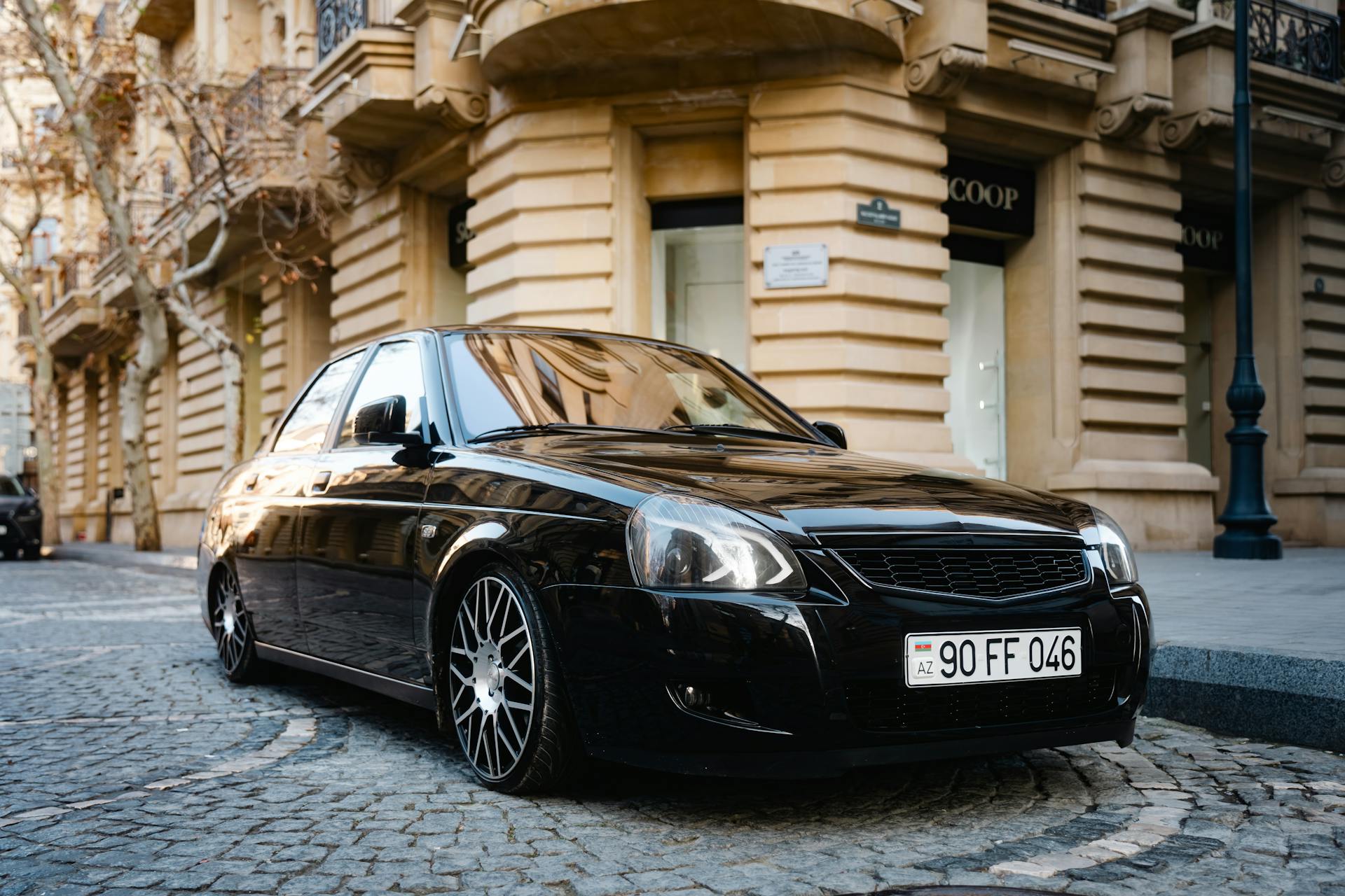 Elegant black luxury car parked on cobblestone street in Baku, Azerbaijan.