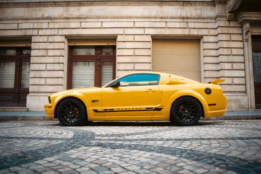Vibrant yellow Ford Mustang sports car parked by a historic building in Baku, Azerbaijan.