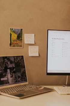 A stylish home office setup featuring a laptop and desktop with modern decor and planning tools.