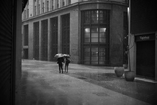 Two people shared umbrellas walking in rainy city street.