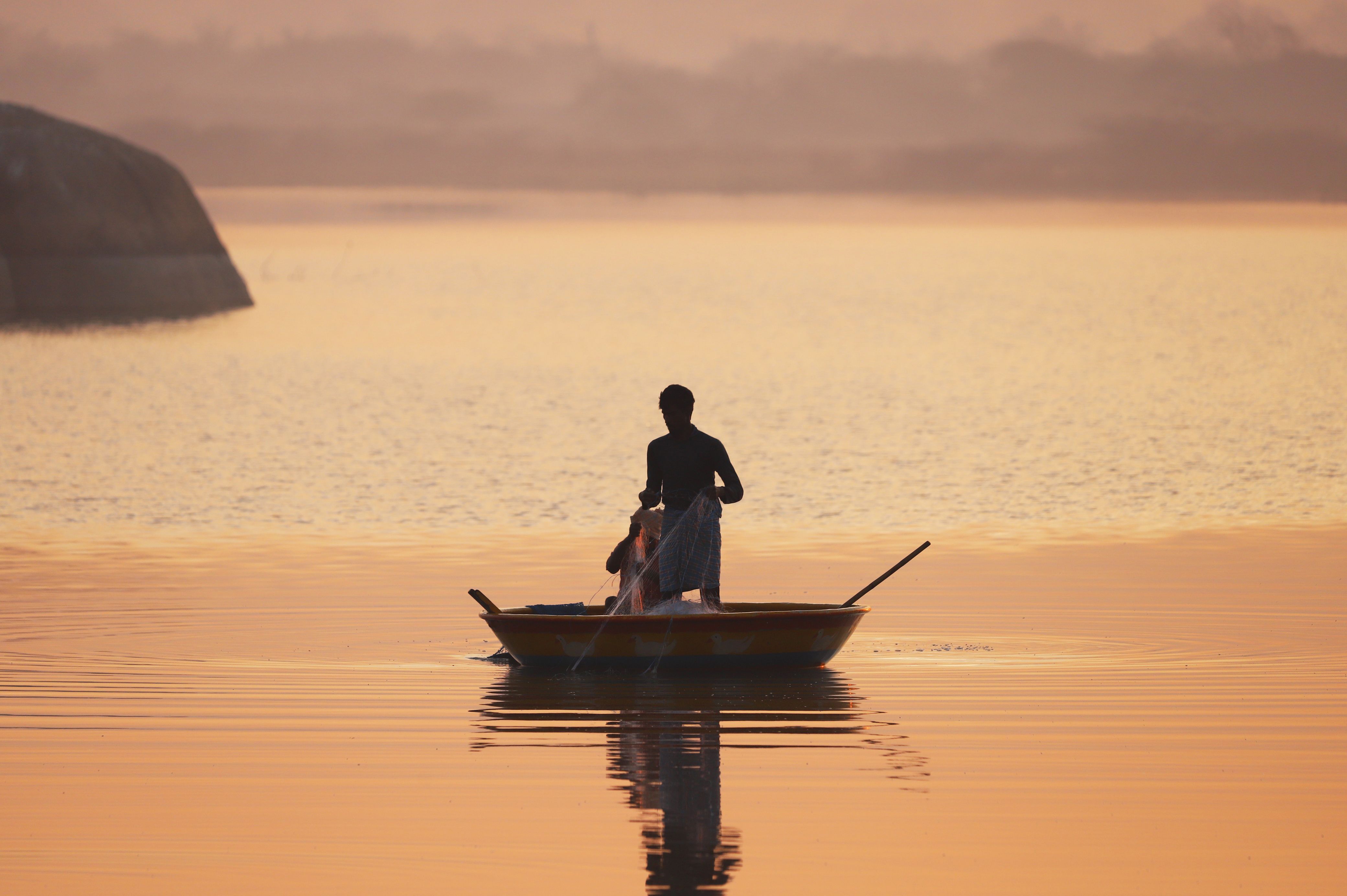 Sunset Silhouette of Fisherman on Tranquil Lake · Free Stock Photo