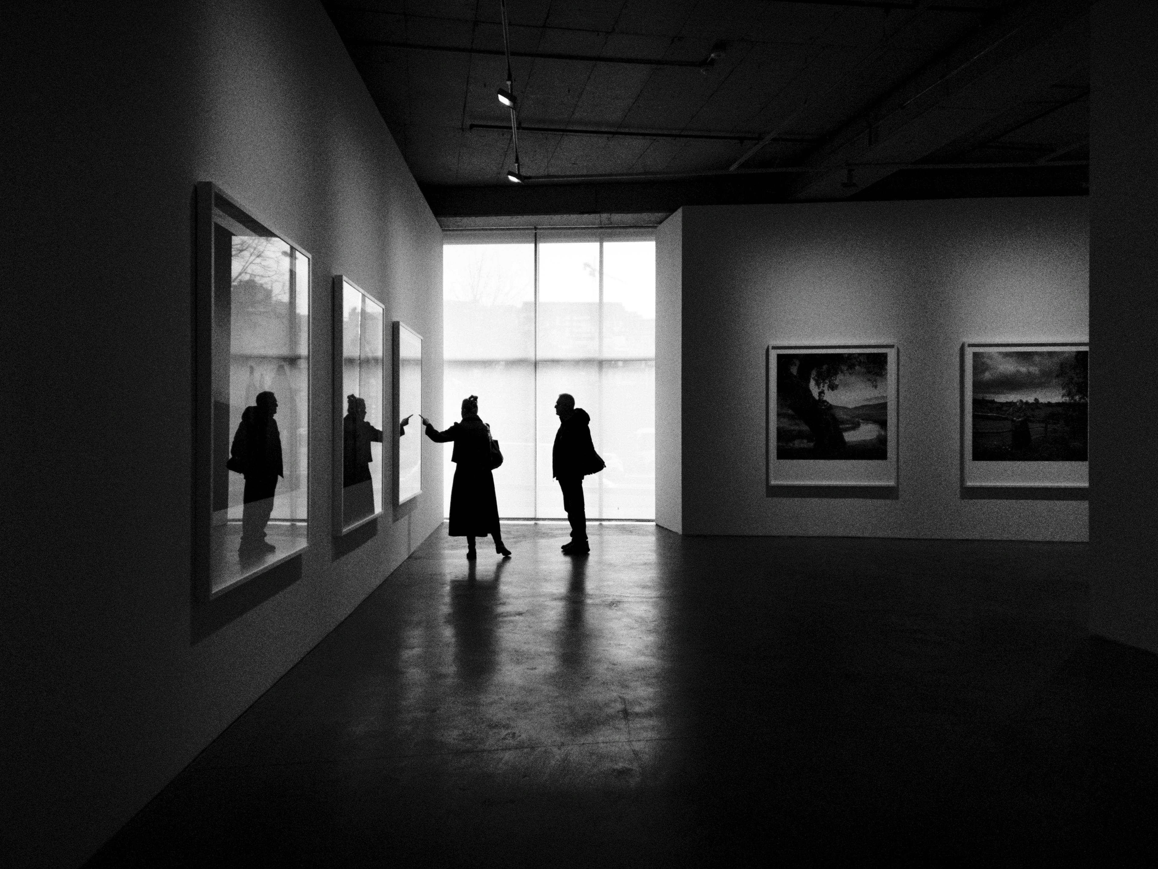 Silhouettes of people exploring an art gallery in Istanbul, capturing a moment of appreciation.