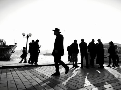 Silhouettes of people by the Bosphorus waterfront in İstanbul, creating a striking black and white scene.