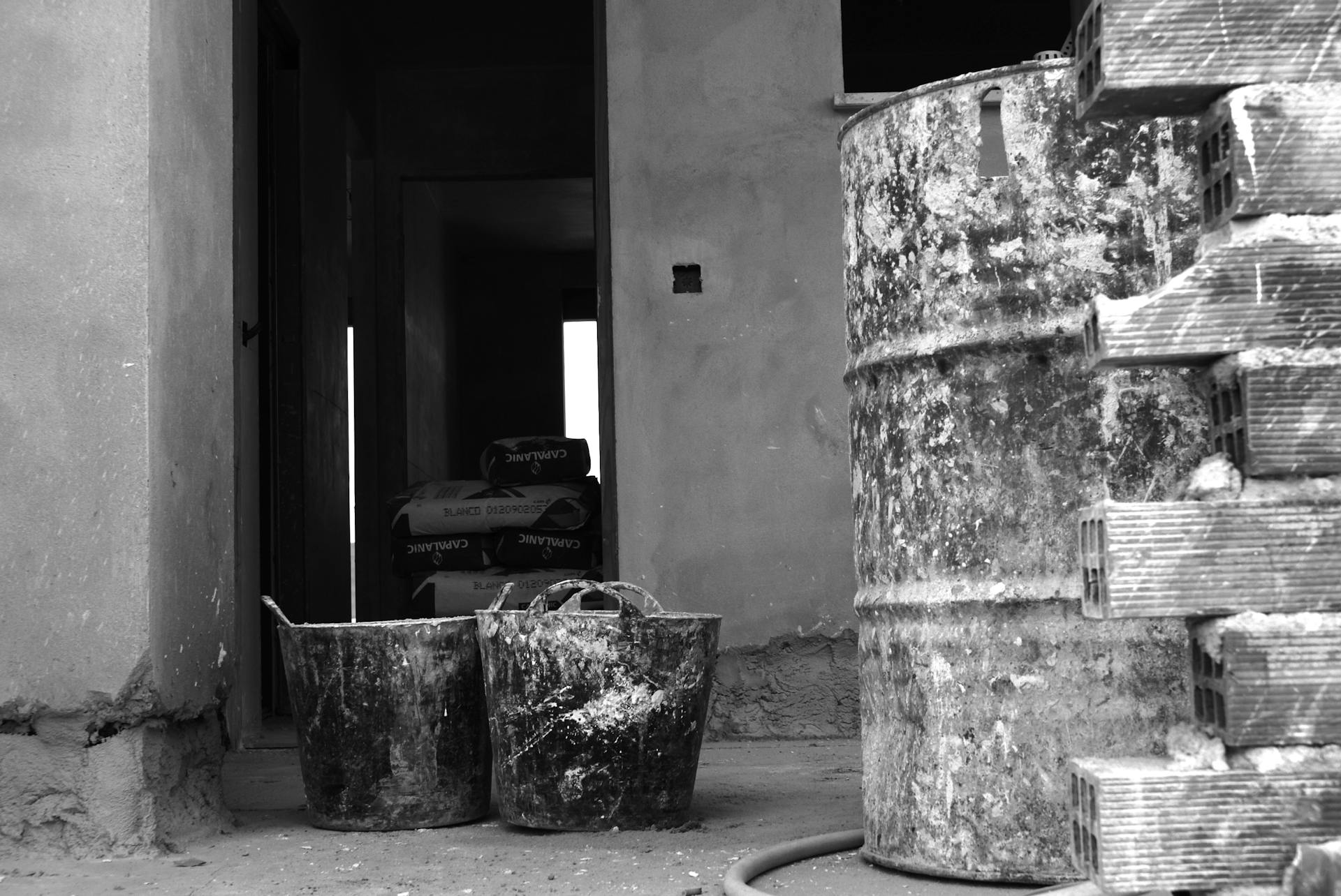 Black and white image of construction site with drums and equipment highlighting industrial atmosphere.