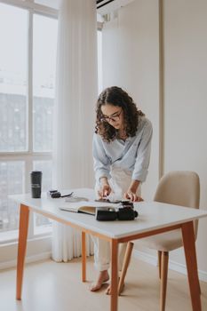 Young woman focusing on work at a desk in a bright modern office environment.