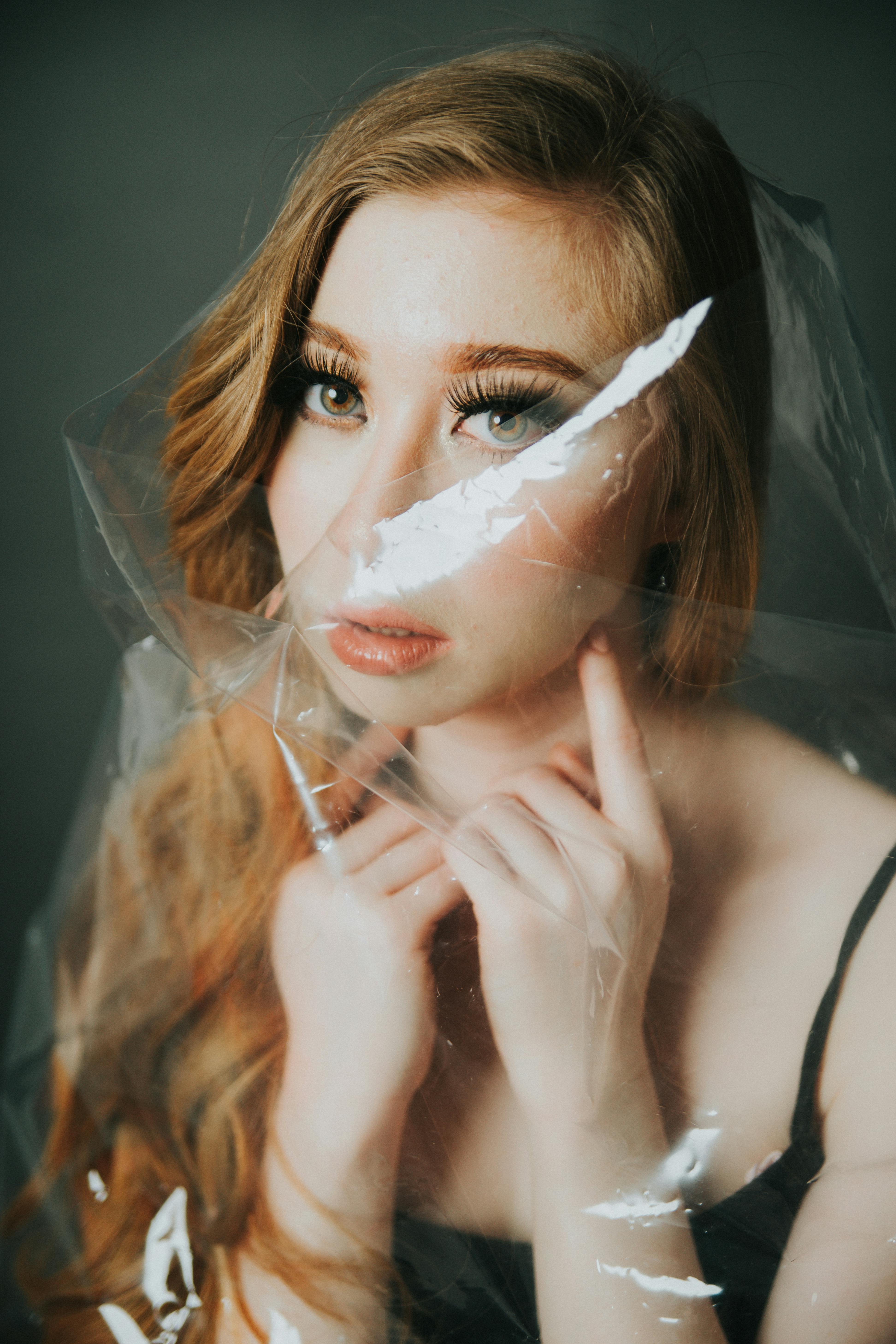 一位化着浓妆的女人的优雅肖像，为了艺术效果，部分被塑料遮住