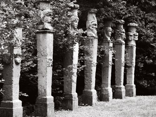Free A row of ancient stone statues in Bomarzo Park, Lazio, Italy, showcasing intricate carvings amidst lush greenery. Stock Photo