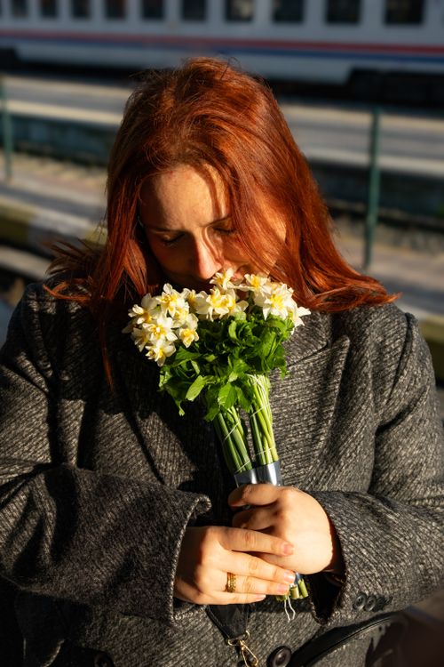 Free Woman smelling white daisies at an outdoor train station in Türkiye. Stock Photo
