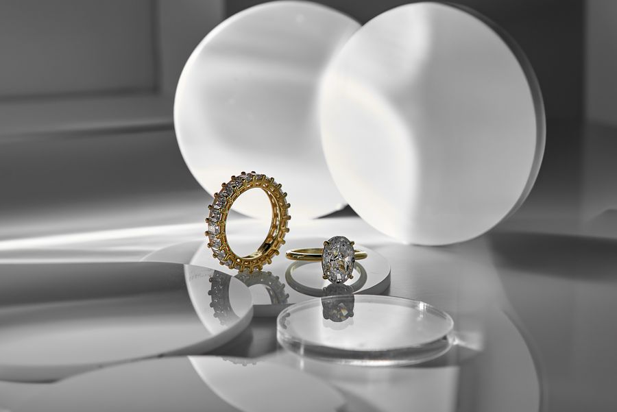 Diamond and gold rings on a reflective surface