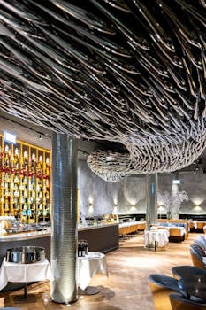 A stylish restaurant interior features a striking black ceiling sculpture and a well-stocked bar.