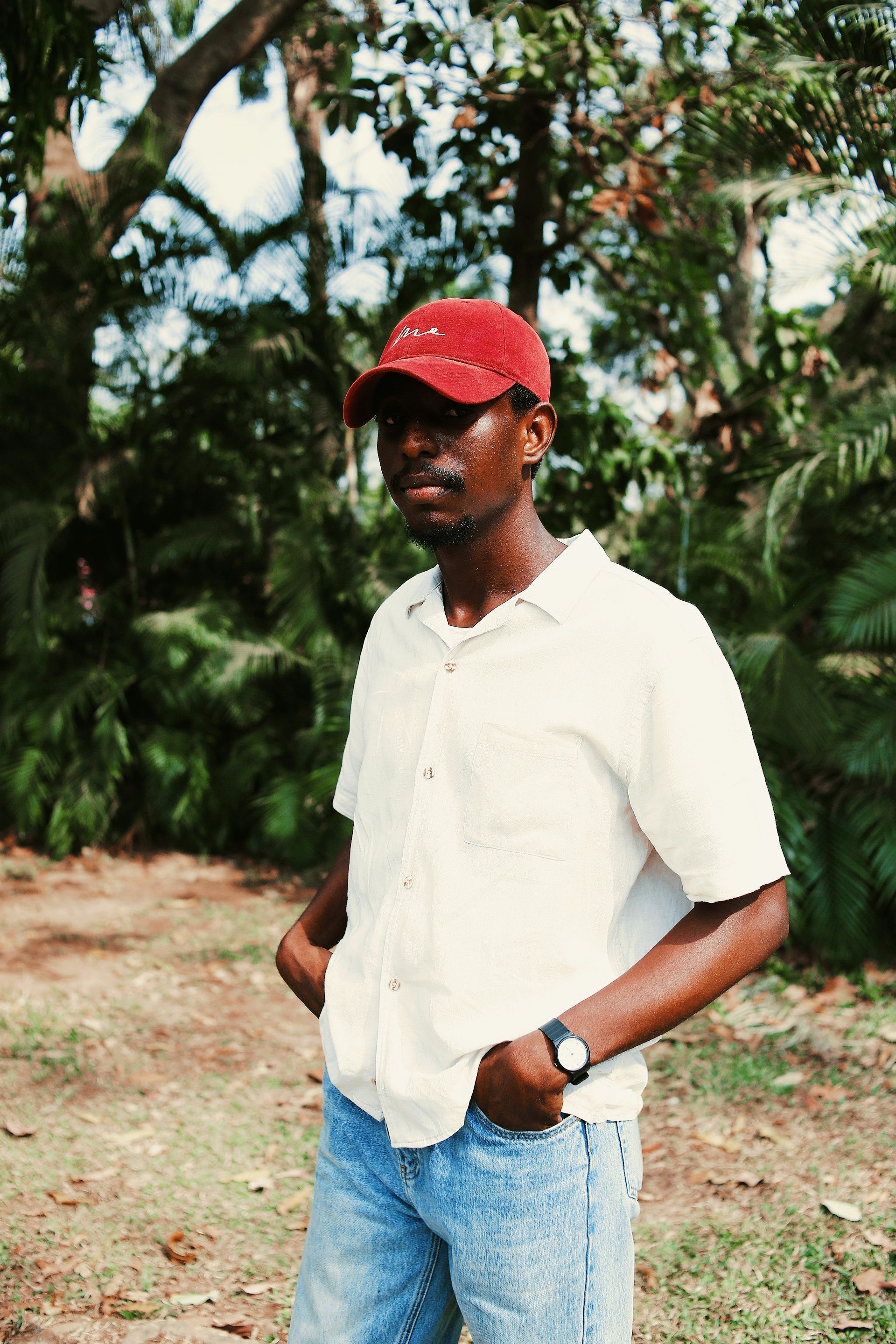 Casual portrait of a young man wearing a red cap in an outdoor setting.
