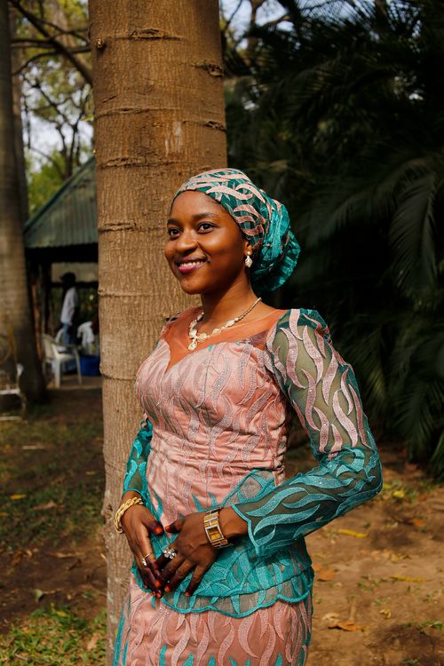 Free Woman wearing colorful Nigerian dress standing by a tree, enjoying a sunny day. Stock Photo