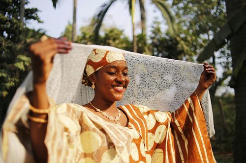 Free Smiling African woman in traditional clothing joyfully posing outdoors in Abuja, Nigeria. Stock Photo