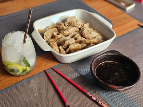 A plate of steaming dumplings with soy dip and a refreshing mint lemon drink.