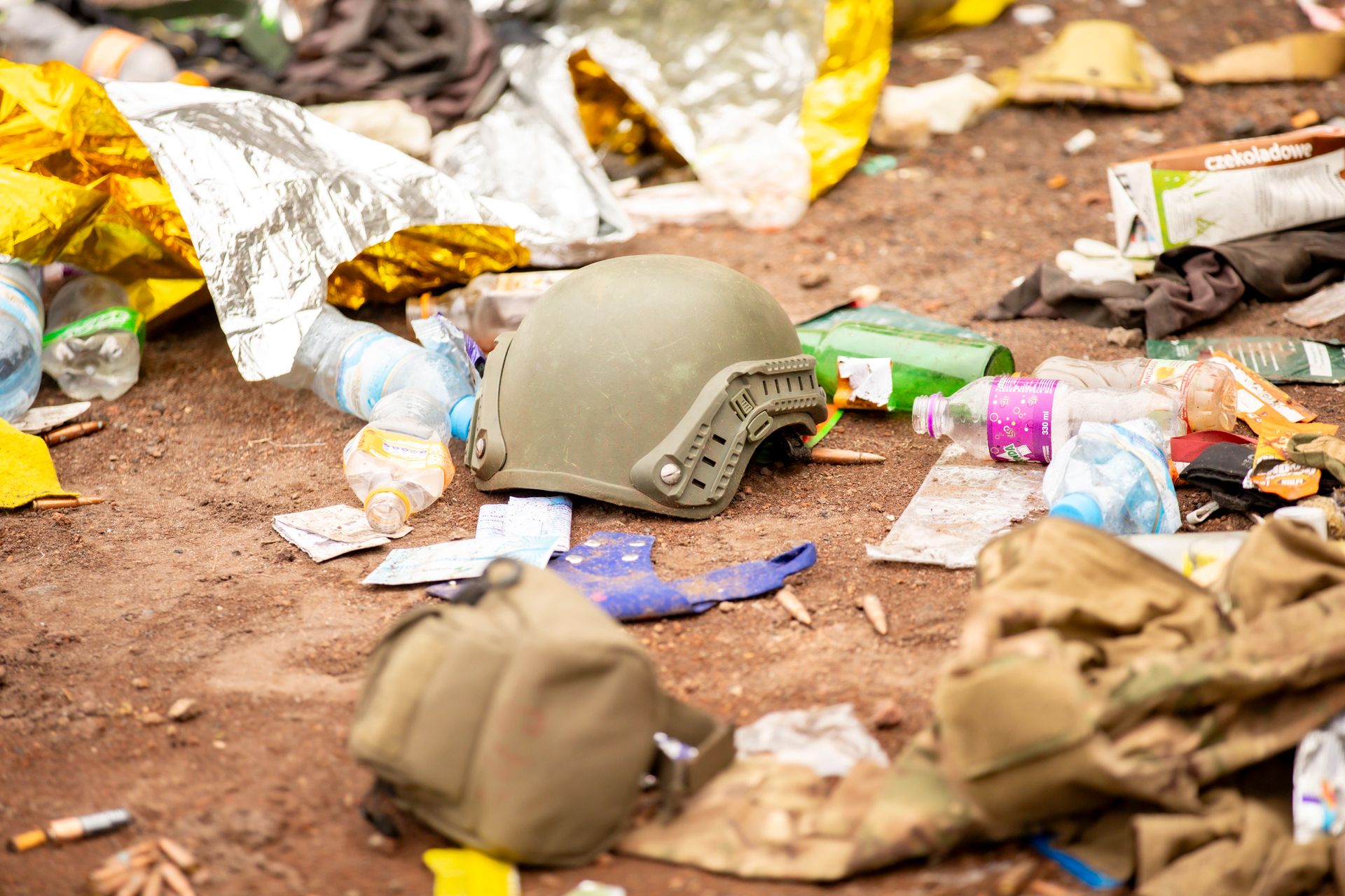 Abandoned military helmet surrounded by litter and debris, depicting a chaotic scene.