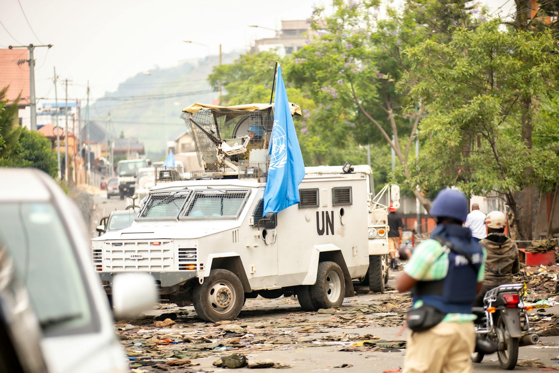 United Nations armored vehicle navigating street amid conflict. Peacekeeping and security presence.