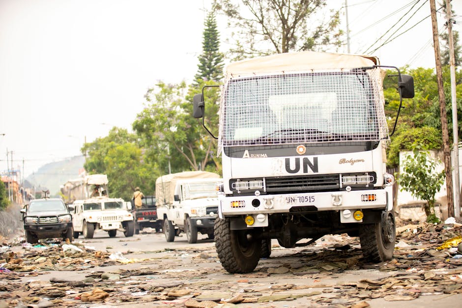 UN vehicles parked on a debris-covered road amid humanitarian efforts.