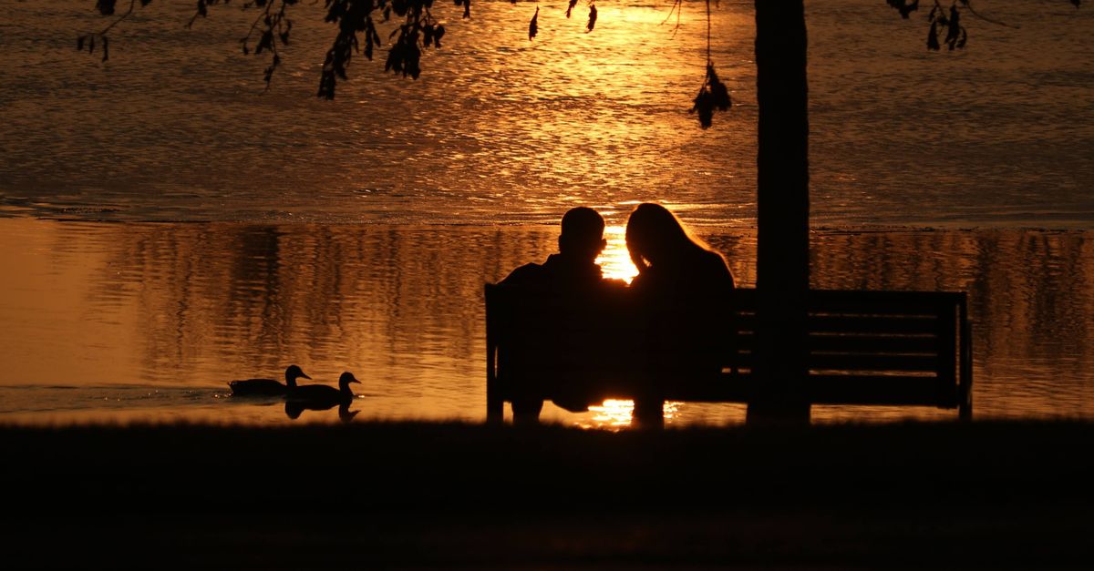 A couple enjoys the serene sunset by the lake in Chicago, Illinois.