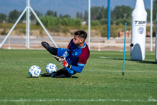 A goalkeeper in full gear practicing saves on a sunny day, showcasing dedication and skill.