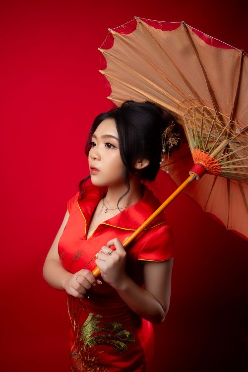 Free Stunning studio portrait of a woman in red cheongsam holding an ornate umbrella. Stock Photo