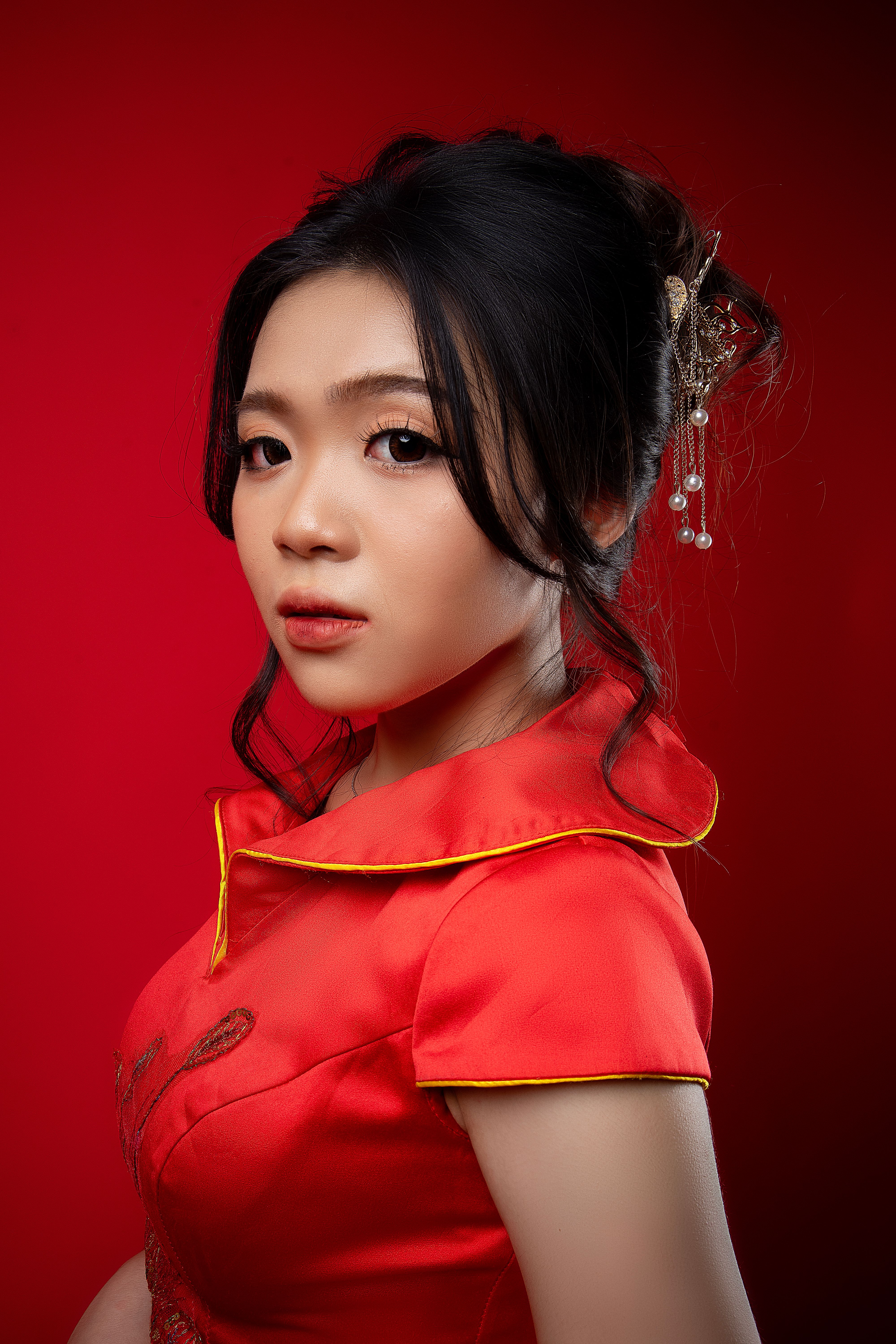 A striking portrait of a woman in a red traditional dress with a rich red backdrop.