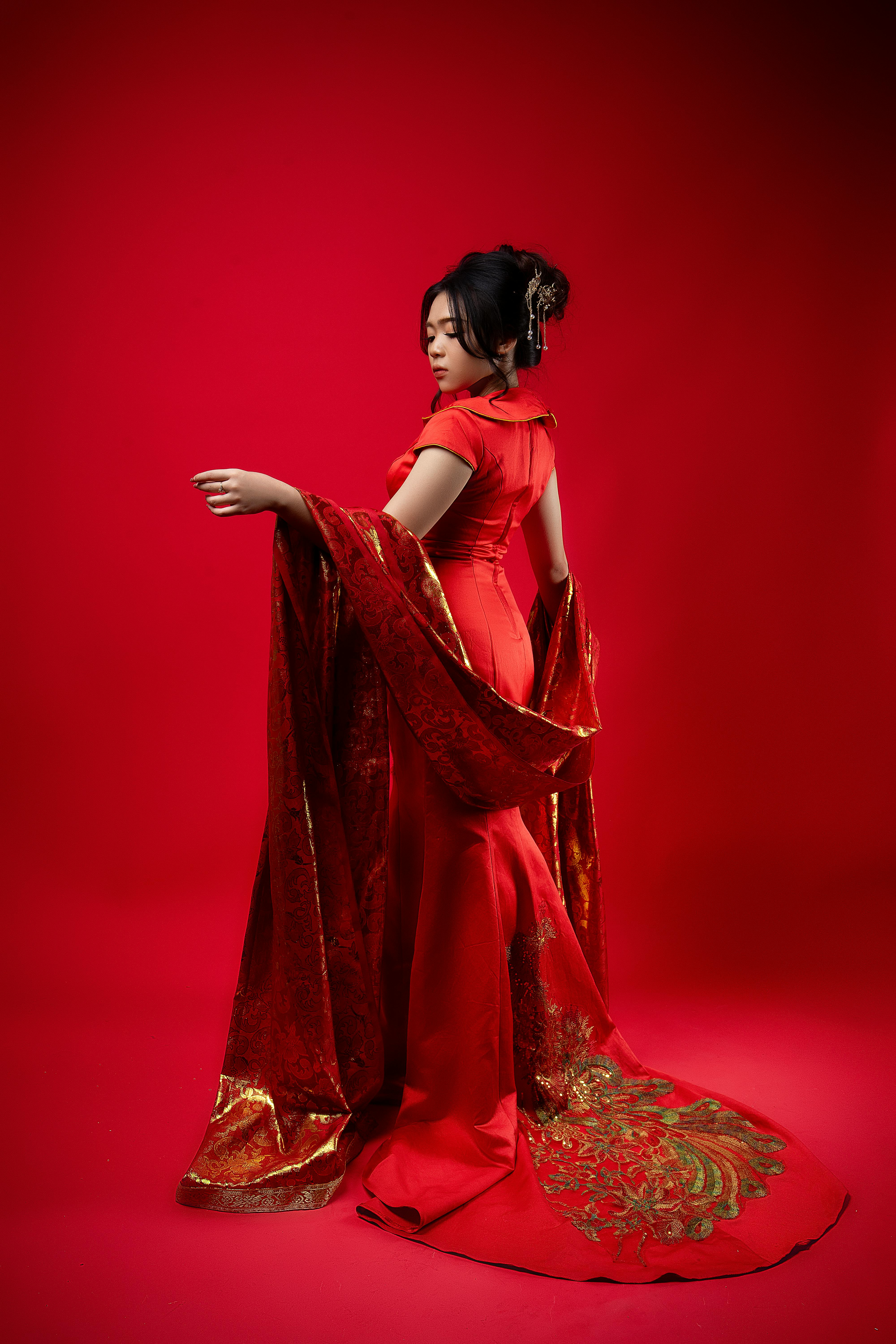 Portrait of an Asian woman in a red traditional dress with elegant pose.