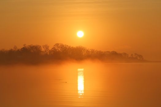 A tranquil sunrise with fog at Cove Island Park, Stamford, Connecticut, showcasing a serene reflection over the water.